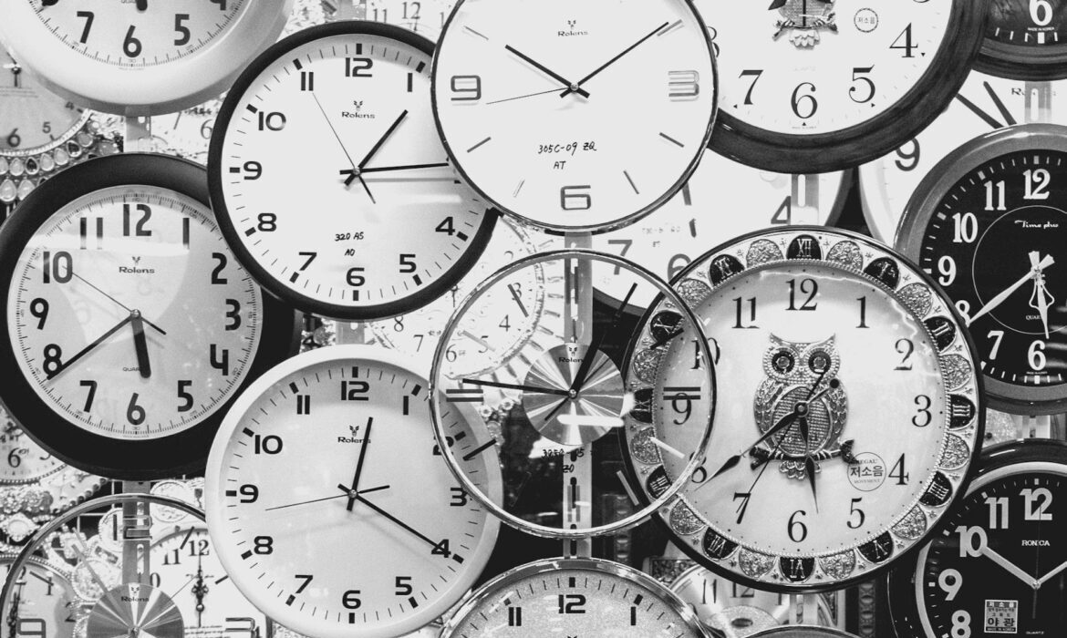 A black and white image displaying a diverse array of vintage wall clocks.